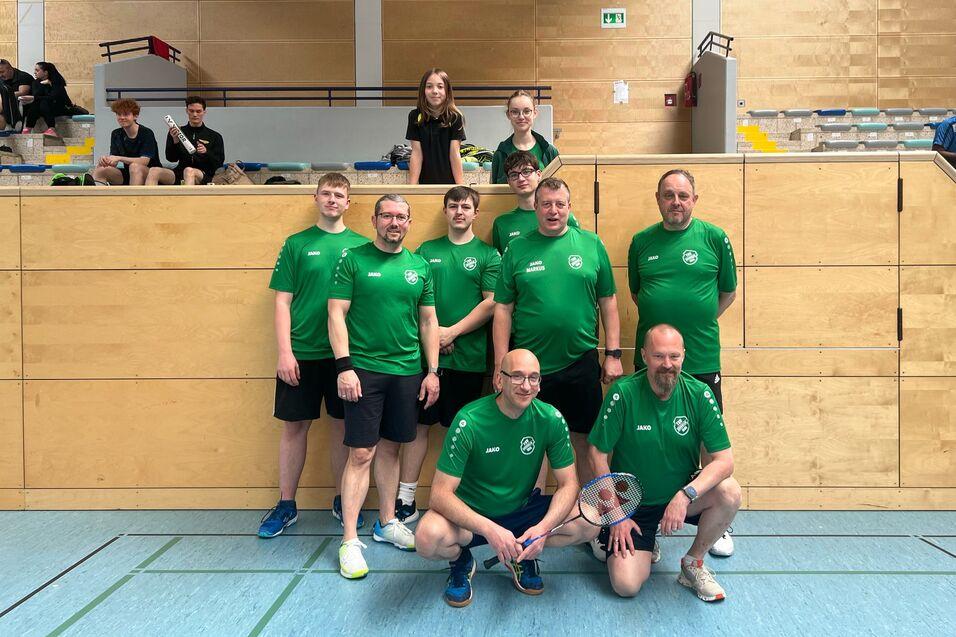 Gruppenfoto von acht Basketballspielern in grünen Trikots, die vor einer Sporthalle posieren.
